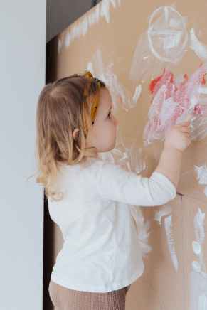 girl in white long sleeve shirt holding paint brush